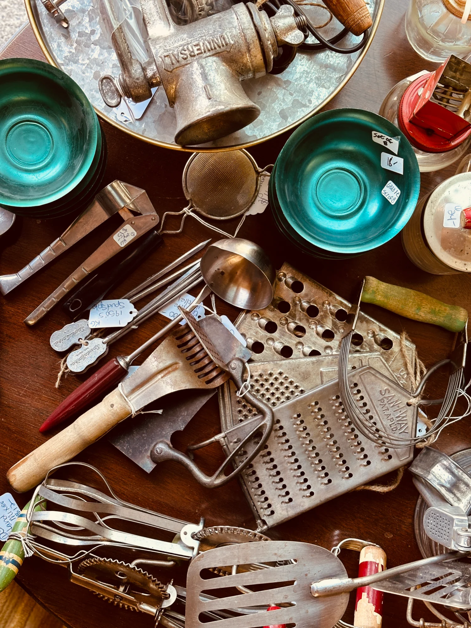 Collection of vintage kitchen tools, graters, and enamelware on display